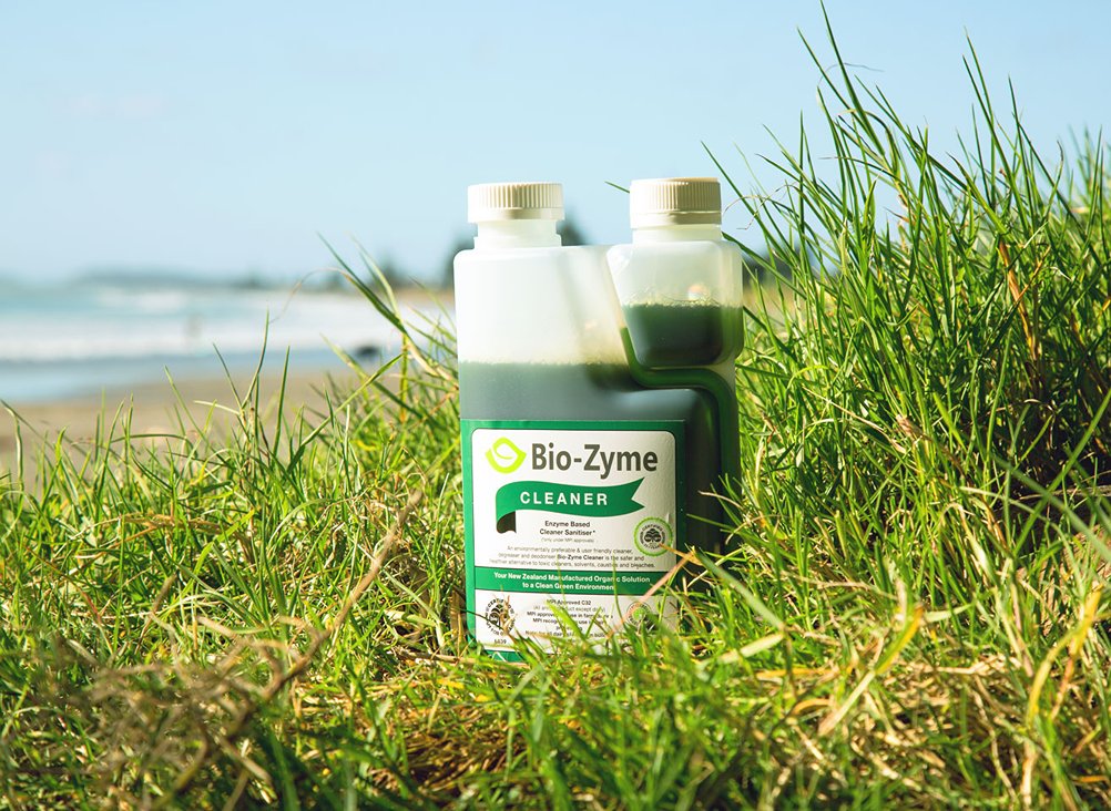 Bio-Zyme Cleaner sitting in the grass, in the beach, showing a blue sky in the background